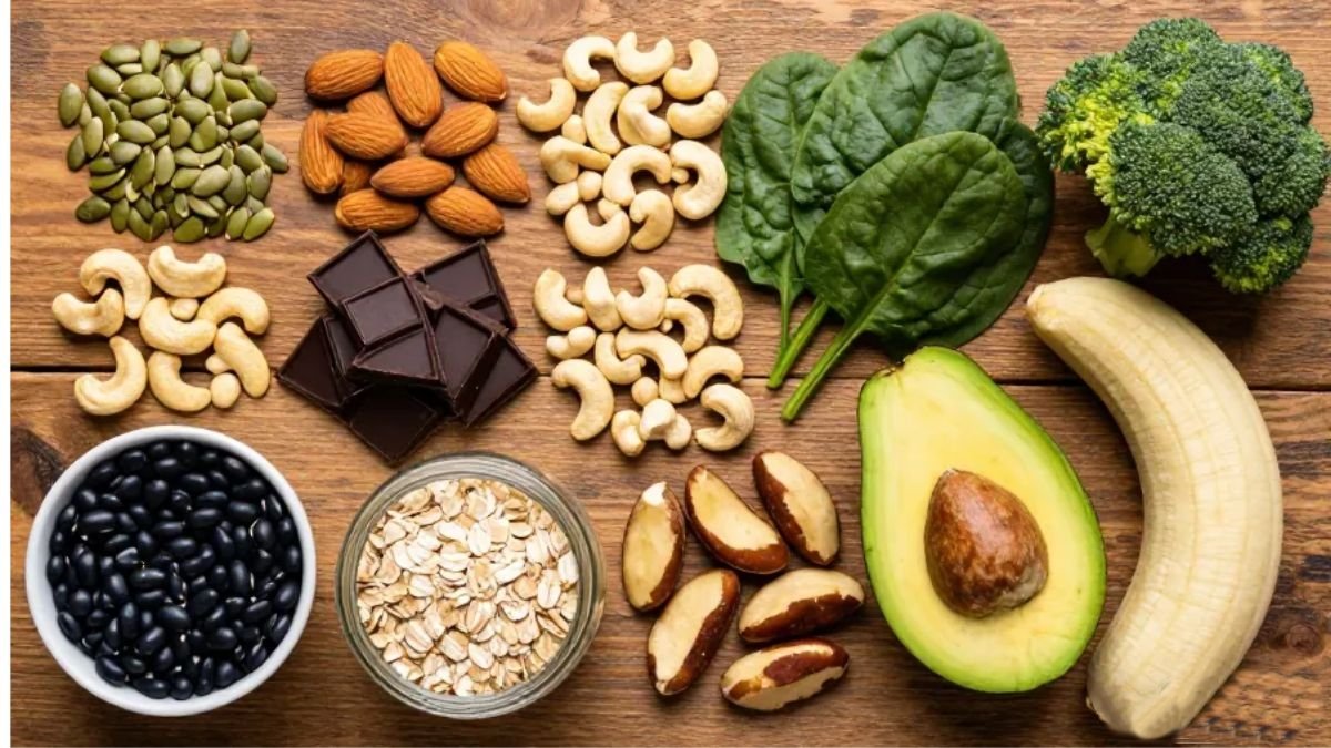 Variedade de alimentos ricos em magnésio sobre superfície de madeira rústica incluindo sementes de abóbora amêndoas castanhas chocolate amargo espinafre feijão preto aveia abacate banana e brócolis